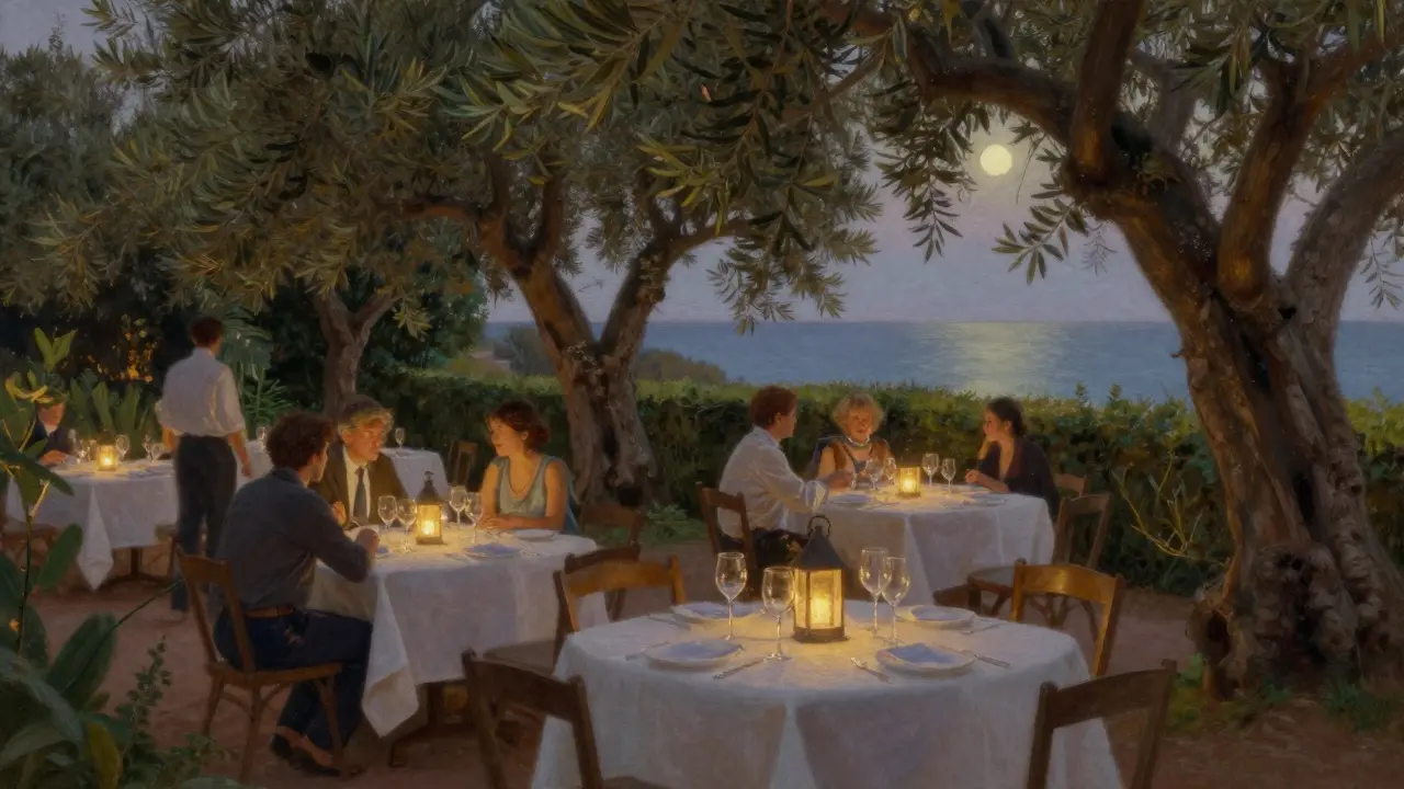 A quiet garden terrace lit by lanterns, with olive trees and distant sea views, where guests enjoy dinner in soft moonlight.